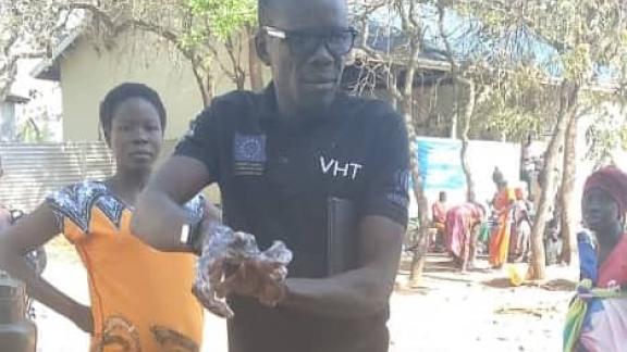 A trained Volunteer Health Team (VHT) demonstrates on hand washing techniques during the outreach at Iyete health care facility in Bidibidi Refugee Settlement