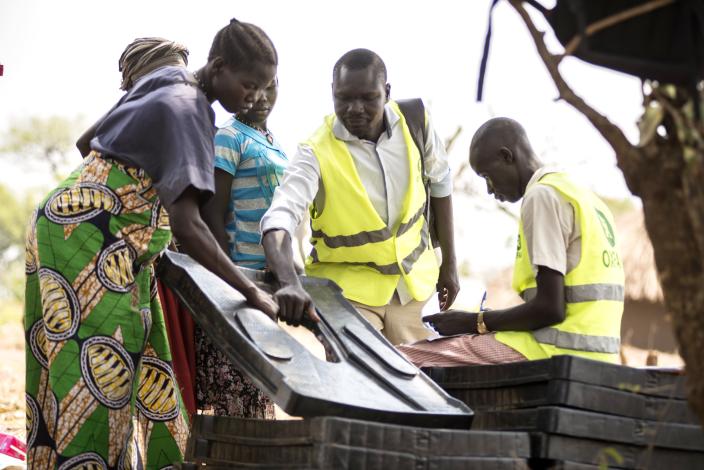 Oxfam volunteers distribute latrine slabs to ensure hygiene. Photo credit: Julius Caeser Kasujja