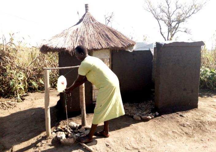 Betty 31 years and single mother of 6 children demonstrates hand-washing at her home latrine Photo: Robert Ariaka/Oxfam
