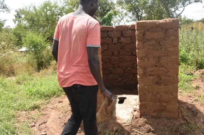 A refugee stands infront of a latrine nearing completion. credit: Oxfam