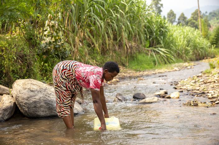 A woman draws water from a stream 