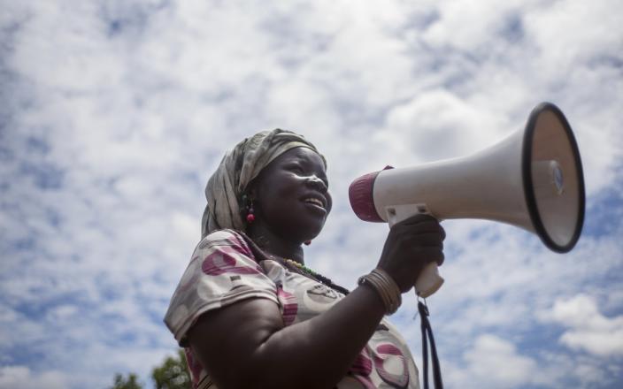 Sarah, the chairperson of a handicrafts group in Bidibidi refugee setttlement, uses a microphone to call women to join her group. Photo:Kieran Doherty/Oxfam