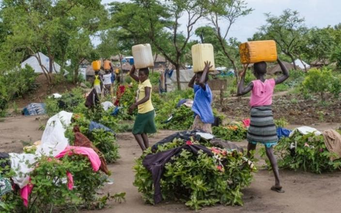 At the Bidi Bidi refugee settlement in Uganda, women carry water back to their shelters. The settlement is now home to more than 287,000 refugees. Photo by Coco McCabe/Oxfam At the Bidi Bidi refugee settlement in Uganda, women carry water back to their shelters. The settlement is now home to more than 287,000 refugees. Photo by Coco McCabe/Oxfam