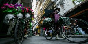 A woman cycles to work in Hanoi. Credit: Dewald Brand, Miran for Oxfam