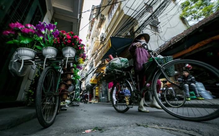 A woman cycles to work in Hanoi. Credit: Dewald Brand, Miran for Oxfam